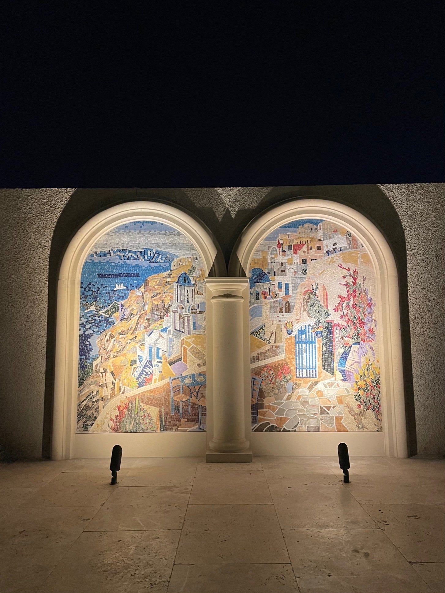 Arched outdoor mosaic murals lit at night