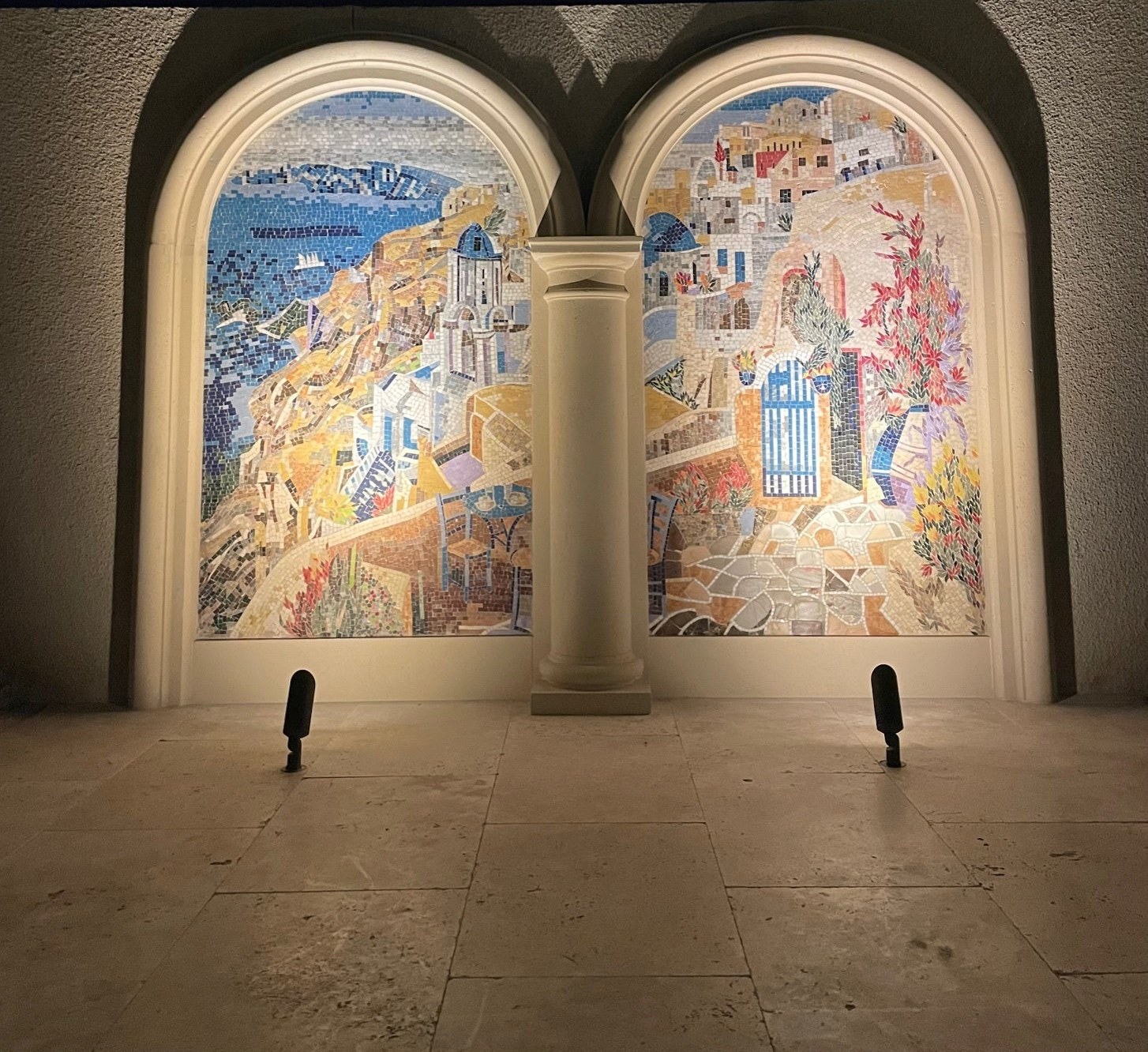 Arched outdoor mosaic murals lit at night